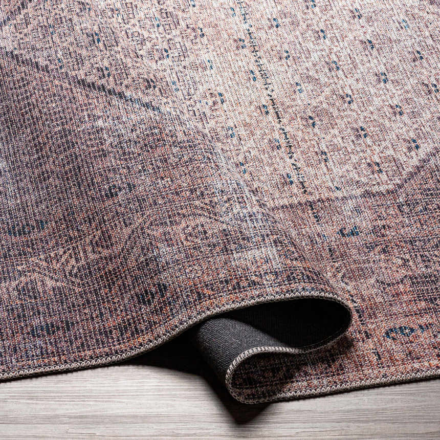Close-up of the Dusty Pink Bagacay Distressed Washable Area Rug showing its cream, pink, and blue oriental pattern. Fold