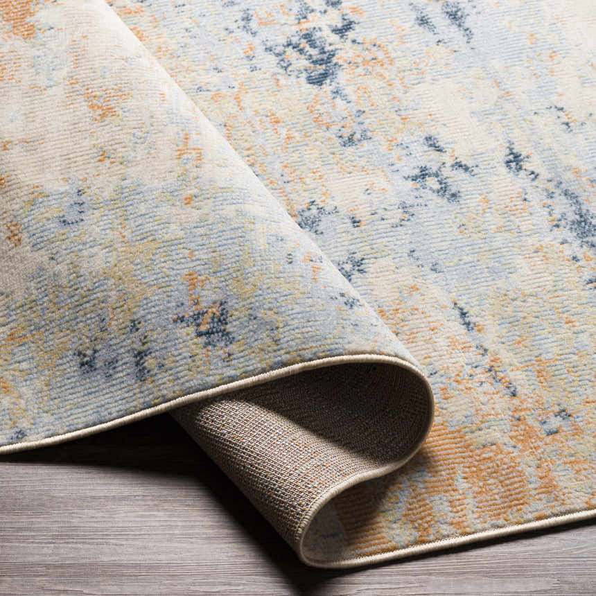 Close-up of the contemporary Bagulin Area Rug. Features a blue, orange, and cream abstract design. Clearance item. Fold