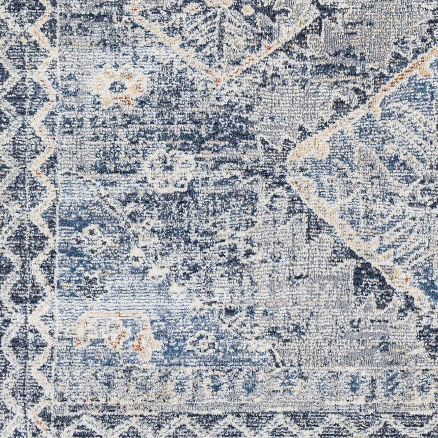 Close-up of the Balamban Area Rug, showcasing its denim, gray, and cream bohemian pattern and soft polyester texture. Swatch
