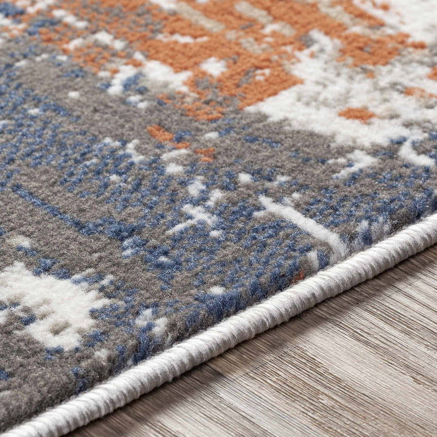 Close-up of the Balerno Area Rug. Contemporary design in charcoal, blue, gray, mustard, terracotta, and white. Machine woven texture. Texture