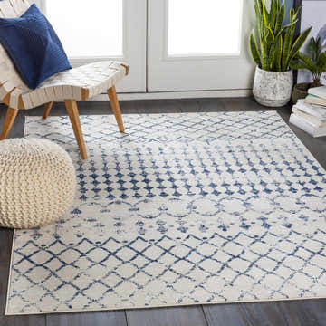 Living room scene with a Banjup Area Rug in dark blue and white, chair, and knit pouf. Roomscene-Rectangle