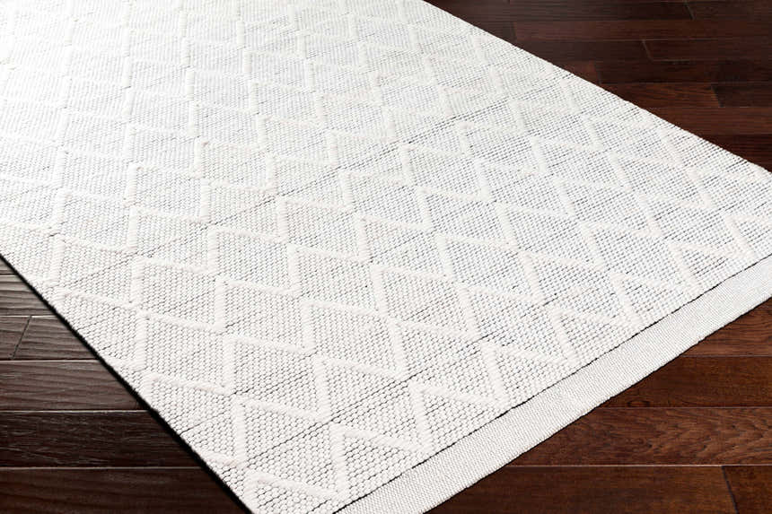 Close-up of the hand-woven Bartimaeus Area Rug, a gray, silver, and nickel rug with a geometric pattern. Corner