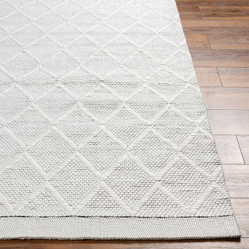 Close up of the hand woven Bartimaeus Area Rug in gray with a geometric diamond pattern on hardwood flooring. Front