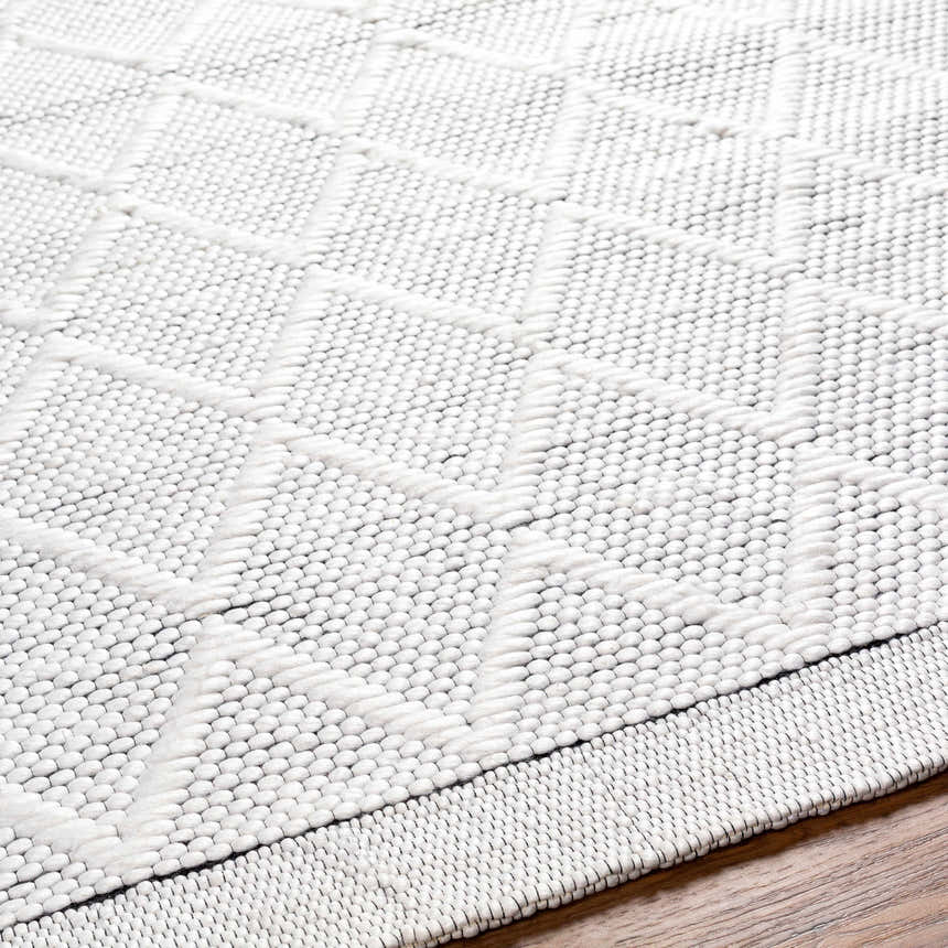 Close-up of the hand woven Bartimaeus Area Rug. Gray and silver tones with a geometric diamond pattern and textured weave. Texture