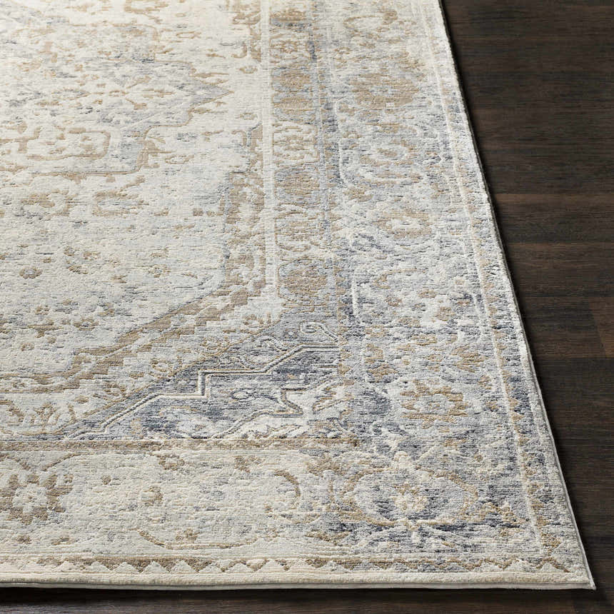 Close up of the Beebe Luxe Area Rug featuring a traditional pattern in ivory, gray, and brown on dark wood floors. Front