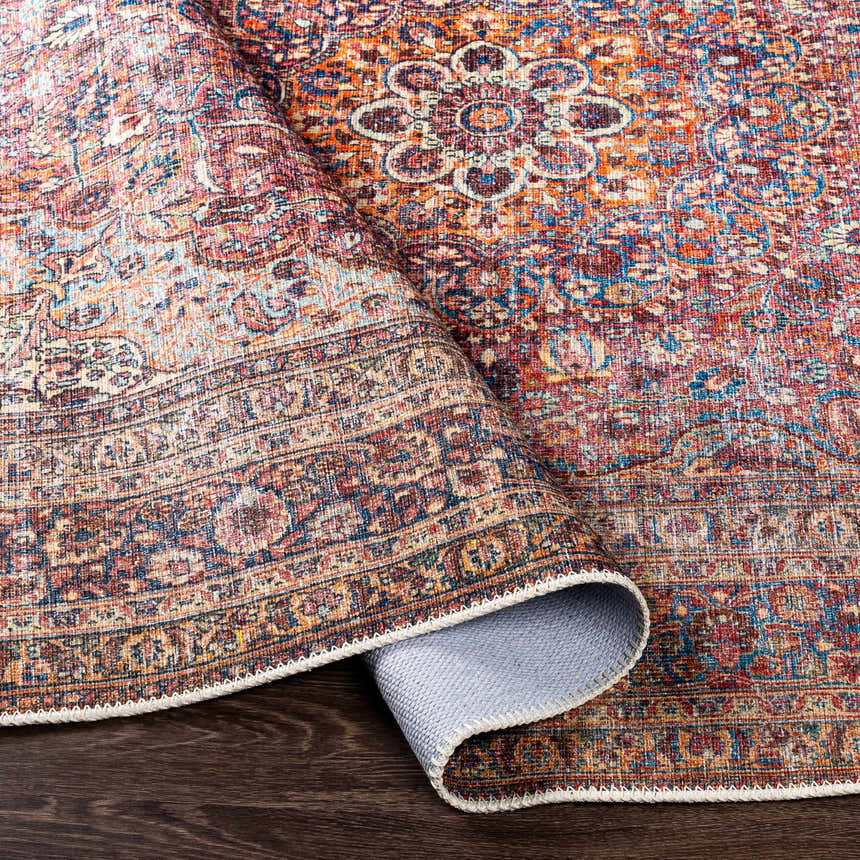 Close-up of the Belison Washable Area Rug showing its traditional floral pattern in orange, red, and blue hues. Fold