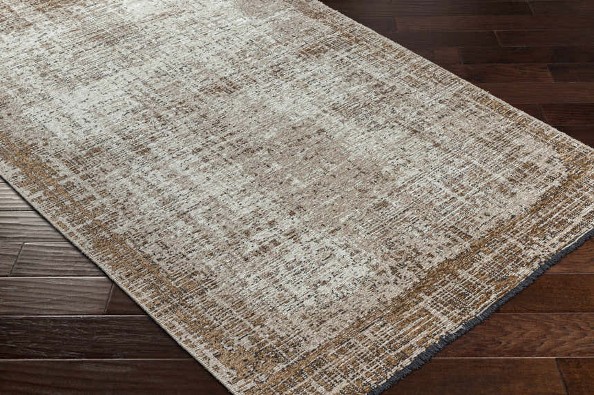 Close-up of the Binh Rustic Brown Rug showing its charcoal, cream, and tan colors and rustic design. Corner