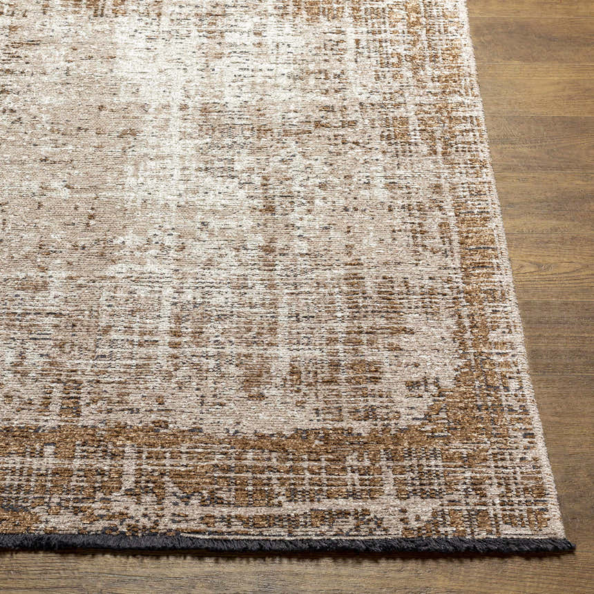 Close-up of Binh Rustic Brown Rug with charcoal fringes. Tan, cream, and charcoal abstract pattern. Front