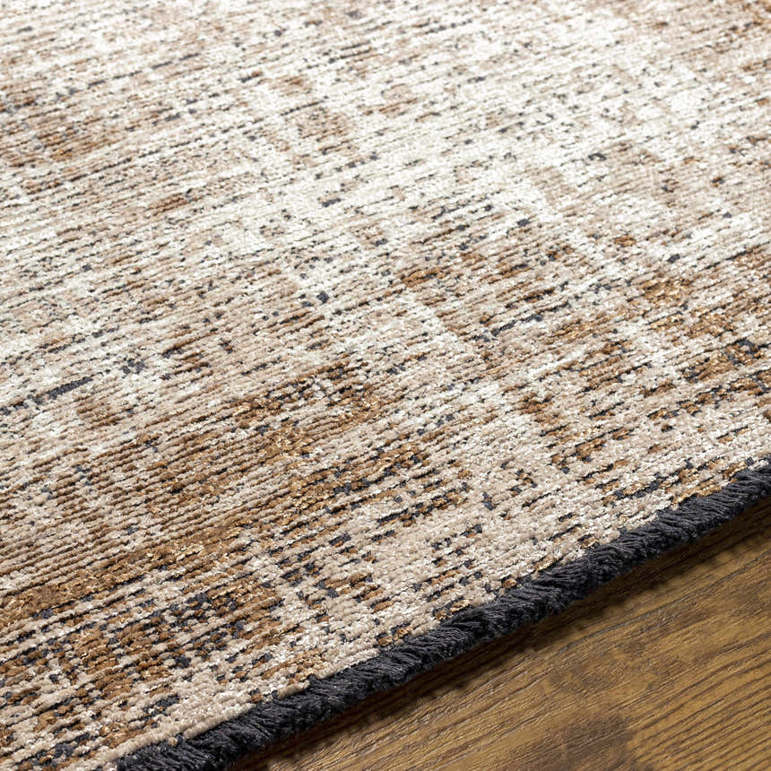 Close-up of Binh Rustic Brown Rug showing charcoal, cream, and tan tones with a subtle pattern and fringed edge. Texture