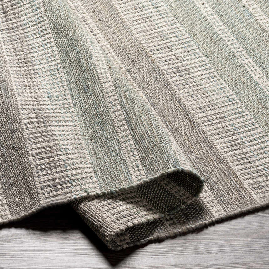 Close-up of the hand-woven Bocana Area Rug. Gray, light beige, sage and seafoam stripes add texture and pattern. Fold
