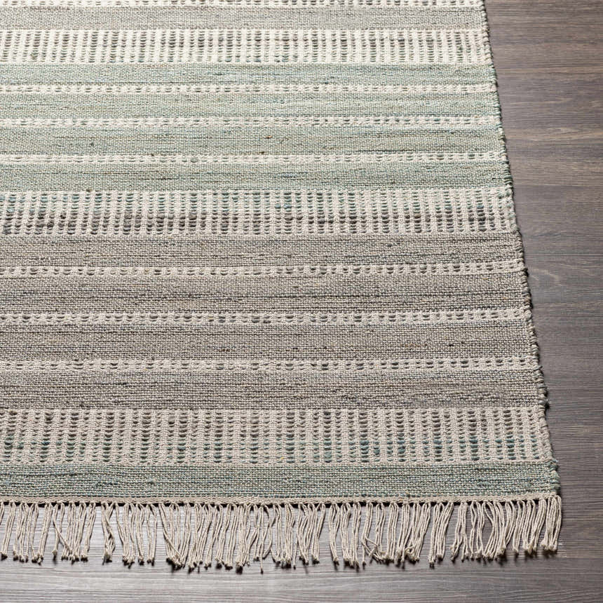 Close-up of the hand-woven Bocana Area Rug. Gray, light beige, peach, and sage stripes with fringe detail. Farmhouse style. Front