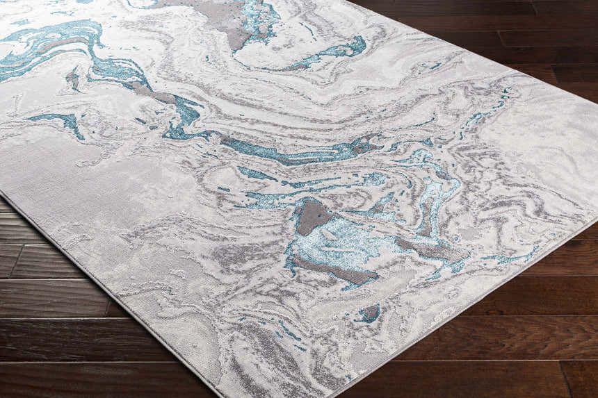 Close-up of the Bonville Blue Marble Rug. Features a contemporary marble-like pattern in blue, cream, beige, and gray. Corner