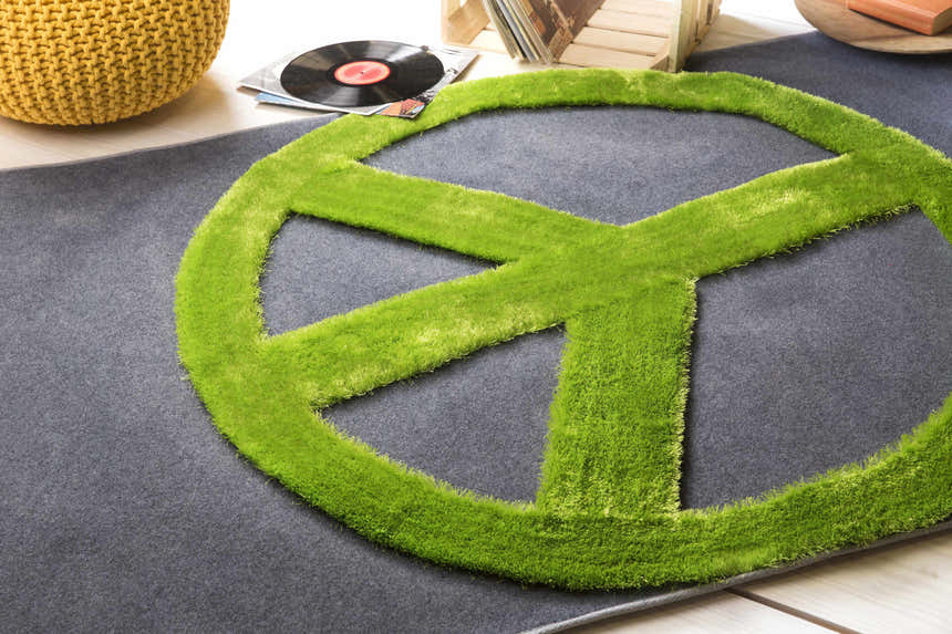 Close-up of the Peace Sign 4x6 Rug. Green peace sign on charcoal rug. Vinyl record and yellow pouf in background. Styleshot