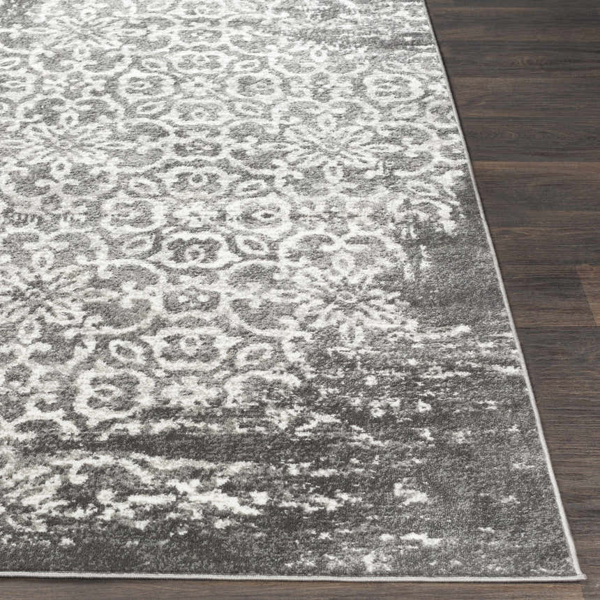 Close-up of the Bowden Carpet - Clearance. Charcoal, light gray, and white floral pattern on dark wood floor. Front
