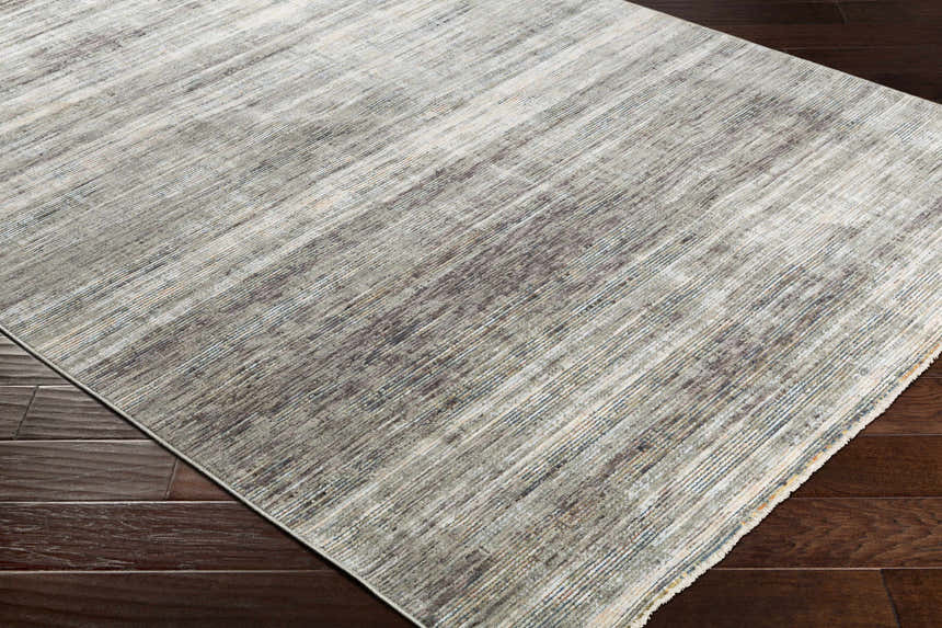 Close-up of the Braxton Carved Statement Area Rug showing its gray, ivory, and brown linear pattern and texture on dark wood floors. Corner