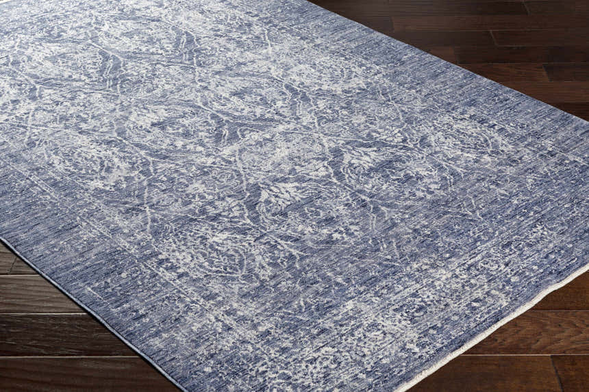 Close-up of the Barboursville Area Rug in denim and light beige, showcasing its vintage, oriental-inspired pattern on dark wood floors. Corner