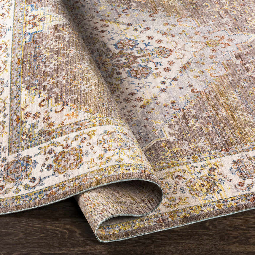 Close-up of the Bourget Area Carpet. Bohemian style rug in brick red, cream, and blue with traditional floral pattern. Fold