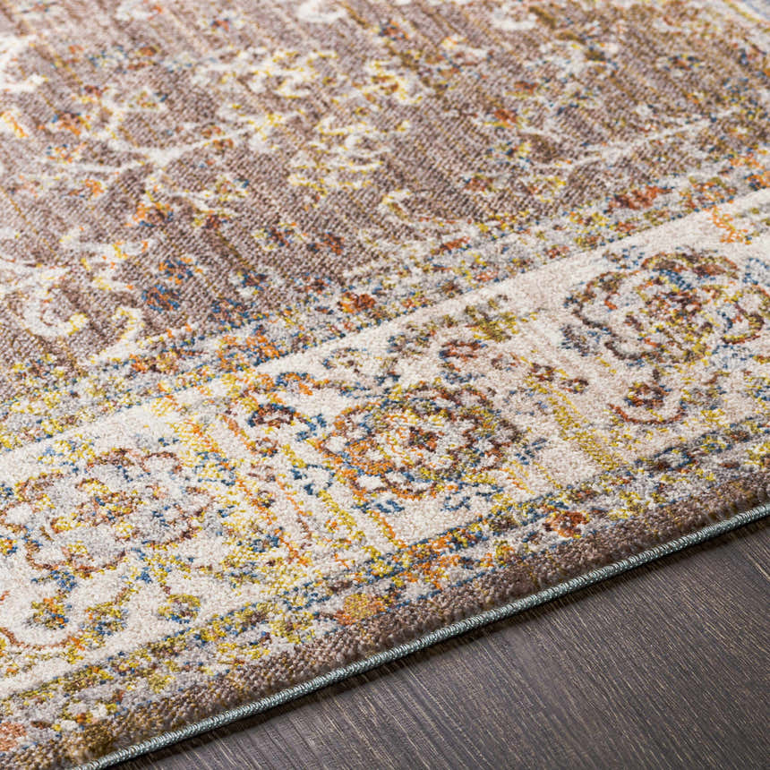 Close-up of the Bourget Area Carpet showing a traditional, floral pattern in cream, gray, mustard, and blue on dark wood flooring. Texture