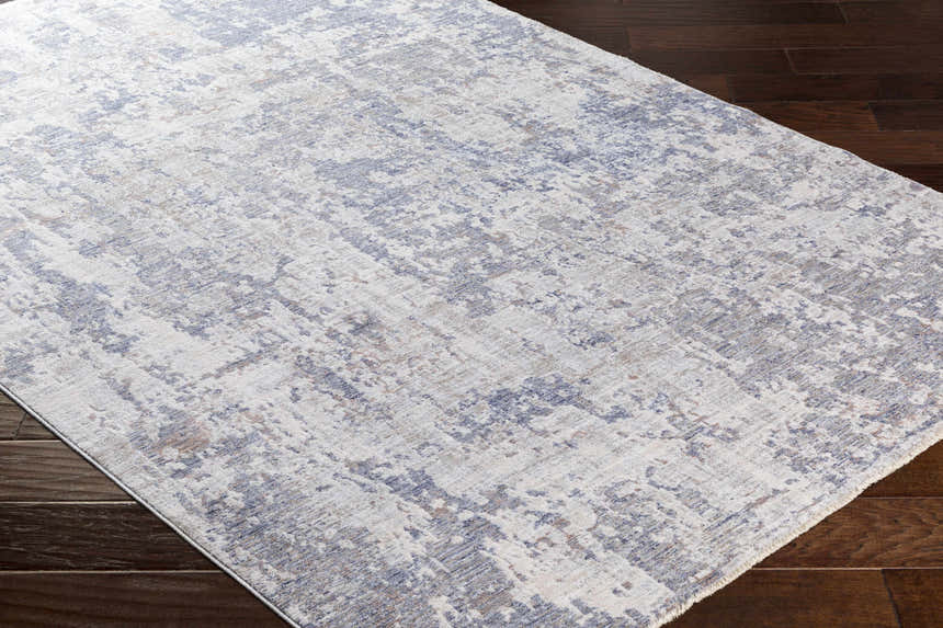 Close-up of the Broxbourne Area Rug showcasing its contemporary design in blush, brown, cream, and denim tones on dark wood floors. Corner