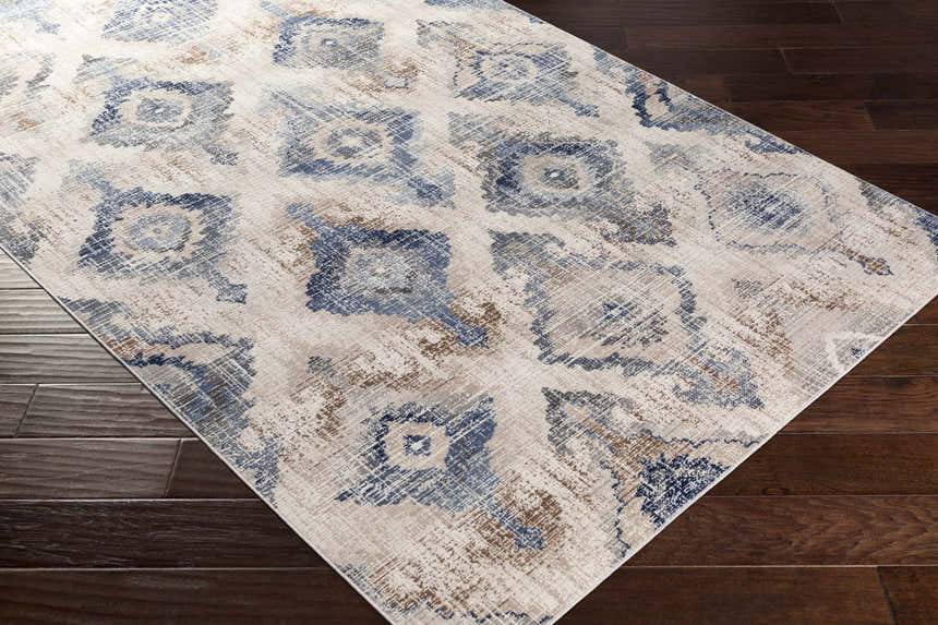Close-up of the Buckner Blue Ikat Rug, a machine-woven rug with a bohemian pattern in denim, gray, brown, and white. Corner