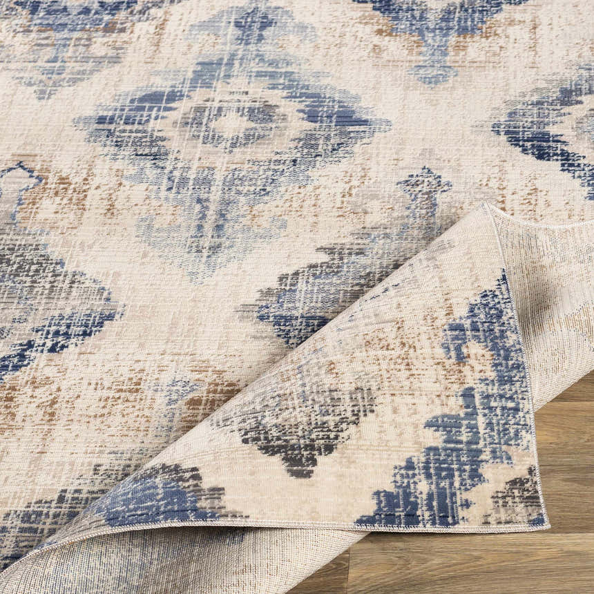 Close-up of the Buckner Blue Ikat Rug showing its bohemian pattern, denim blue, brown, and gray colors. Fold