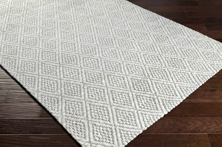 Close-up of the hand woven Budgewoi Jute Rug. Bleached jute, cream, and gray diamond pattern. Contemporary style. Corner