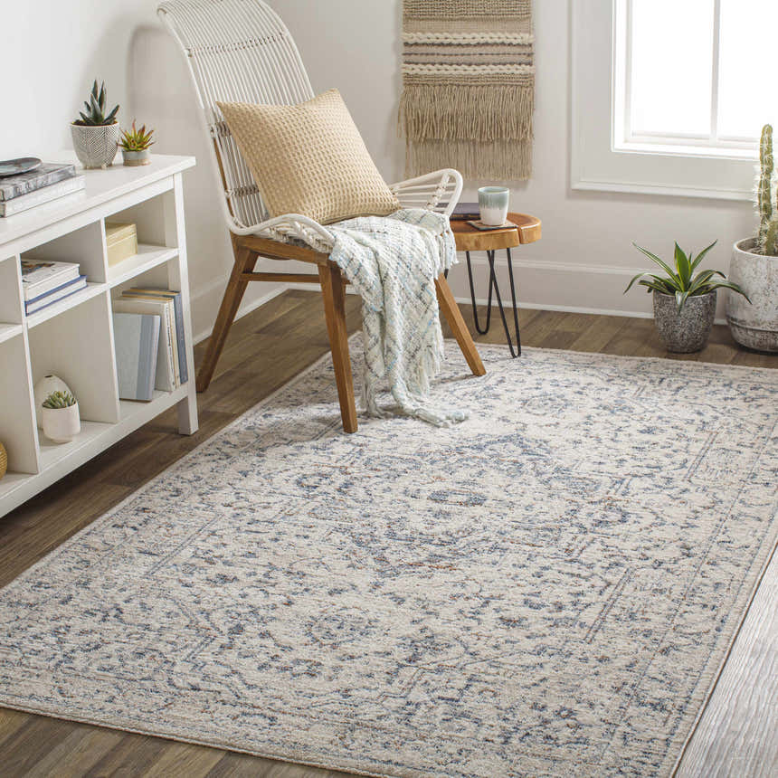 Bohemian room scene with Buguey Area Rug in cream and blue. Wicker chair, wood floors, and neutral decor create a cozy space. Roomscene-Rectangle