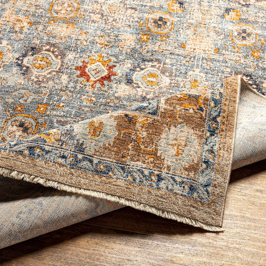 Close-up of the Buldon Area Rug, showcasing its dark beige, brown, peach, mocha, and taupe oriental pattern. Fold