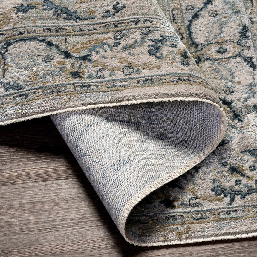 Close-up of the Bushnell Thick Luxe Boutique Rug showing its traditional pattern, dusty sage, beige, and teal colors. Fold