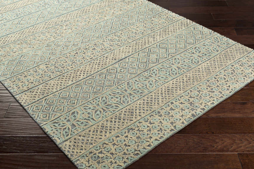 Close-up of the Byron Area Rug: beige, charcoal, and sage geometric patterns on a hand-tufted wool rug. Corner