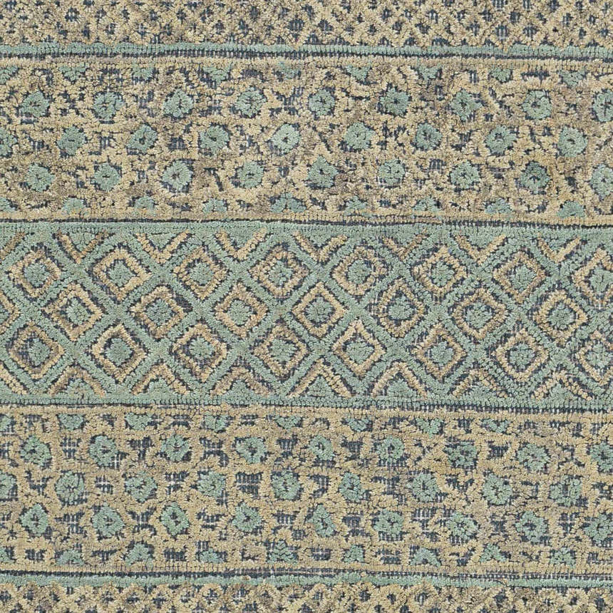 Close-up of the Byron Area Rug with a geometric and floral pattern in beige, charcoal, and sage wool. Swatch