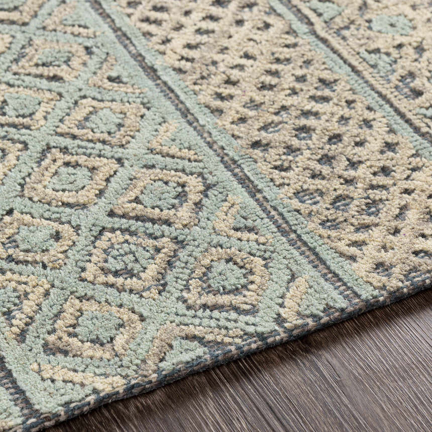 Close-up of the hand-tufted Byron Area Rug. Beige, charcoal, and sage wool with a bohemian-inspired geometric pattern. Texture