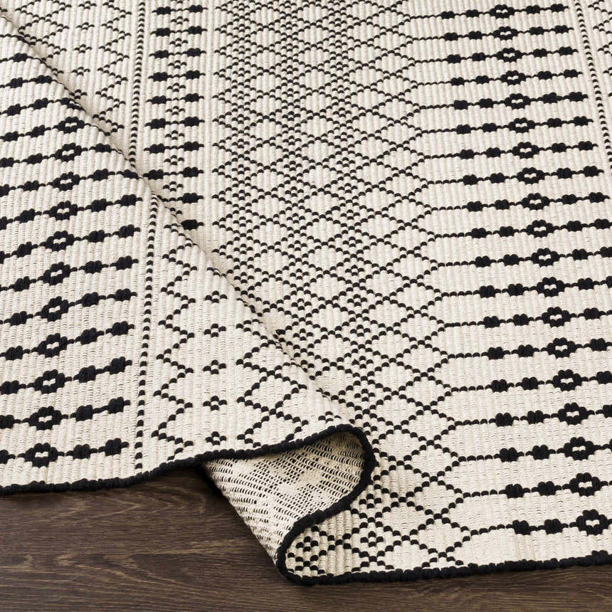 Close up of the hand woven Cabinuangan Area Carpet. Beige cotton rug with a black Southwestern geometric pattern. Fold