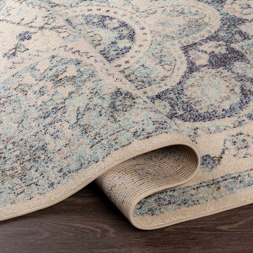 Close-up of the Calpine Area Carpet showing its cream, blue, and gray oriental design and plush texture. Fold