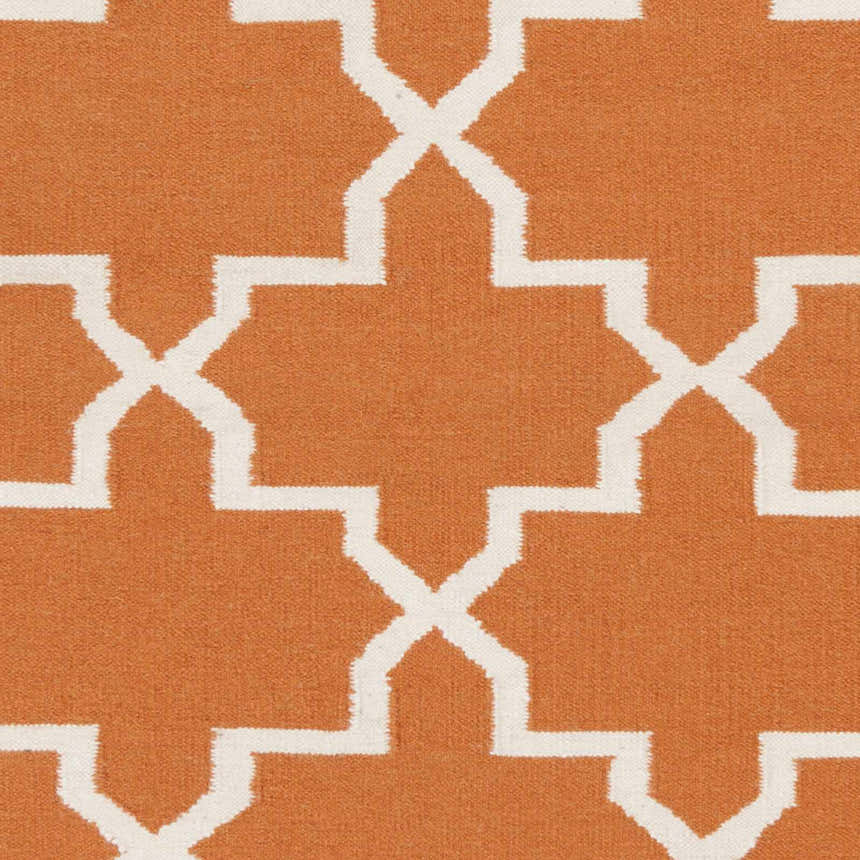 Close-up of the Canadys Area Rug, a hand-woven wool rug with a white geometric pattern on a burnt orange background. Swatch
