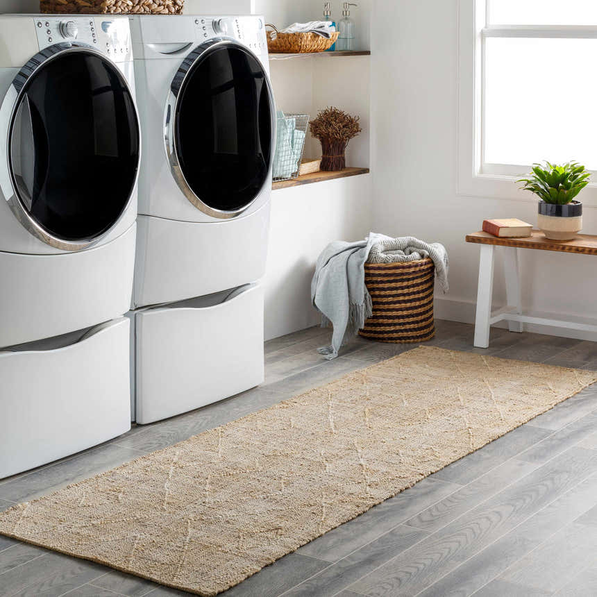 Laundry room scene with beige Carine Jute Area Rug runner, white washer/dryer, gray floors, and natural accents. Roomscene-Runner