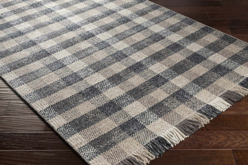 Close-up of the hand-woven Chilliwack Gray Plaid Wool Rug showing charcoal, cream, and gray tones with fringe detail. Corner