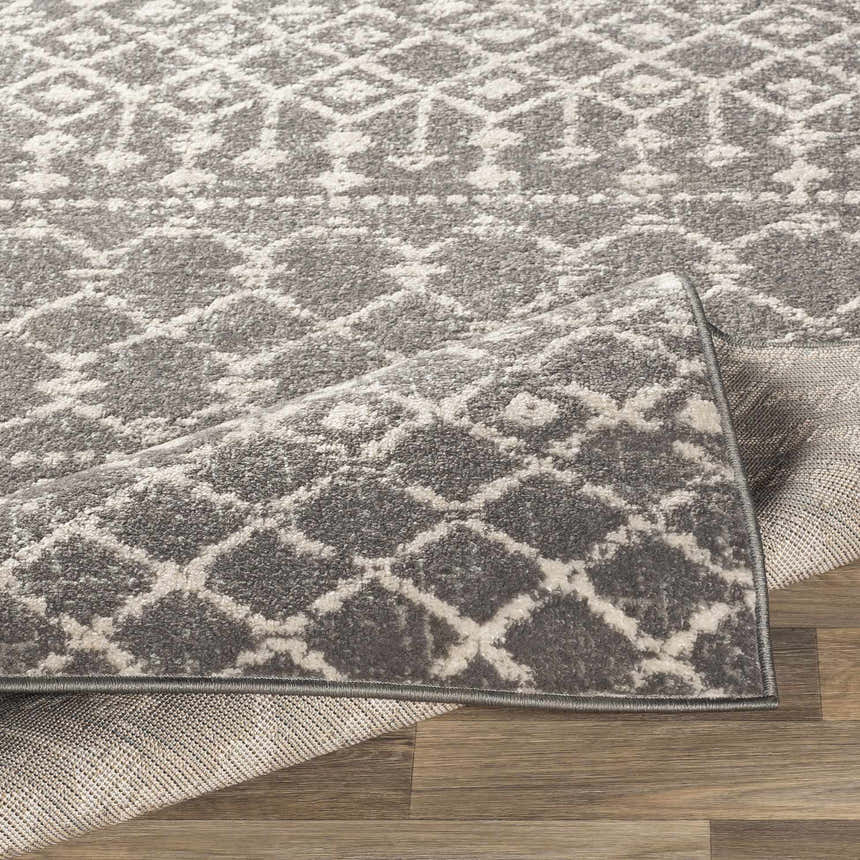 Close-up of the Cliffwood Area Rug showing its charcoal and light beige geometric pattern and machine-woven texture. Fold