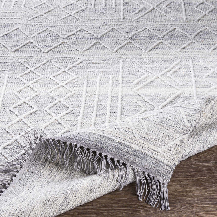 Close-up of the Gray Clintwood Wool Tassel Carpet showing the textured geometric pattern and tassel fringe detail. Fold