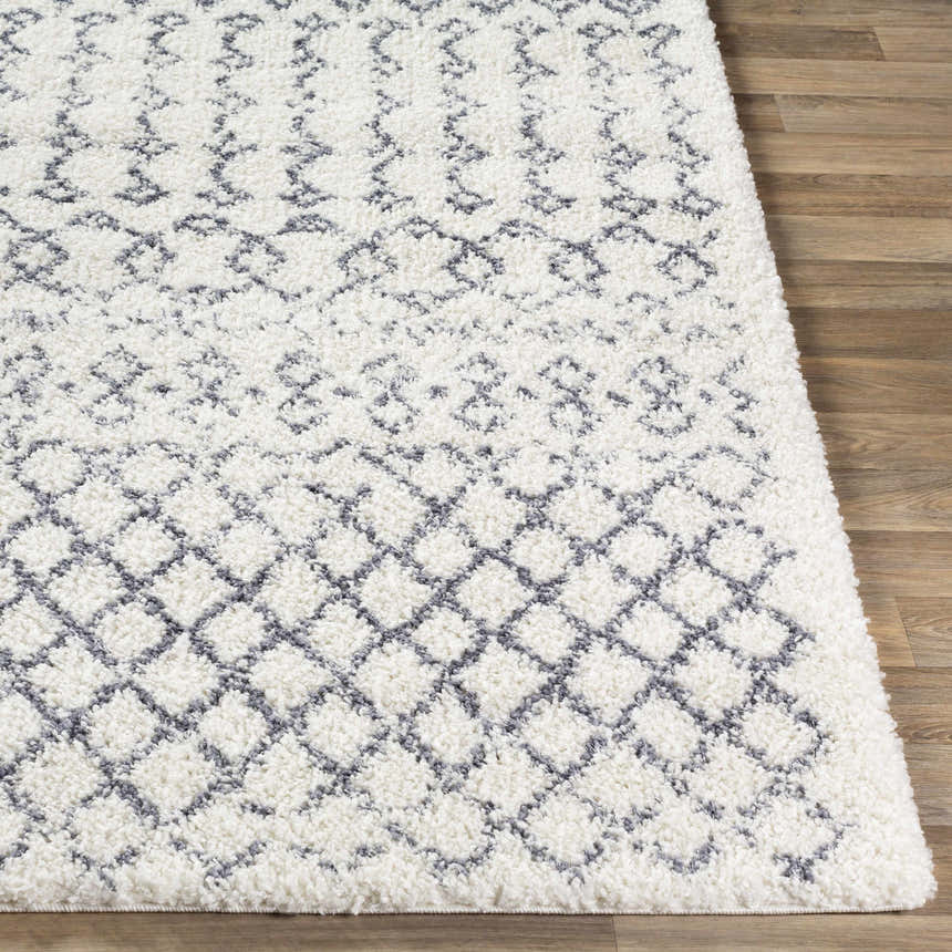 Close-up of the shaggy Clarkia Area Rug. Features a geometric gray and white pattern on a wood floor. Front