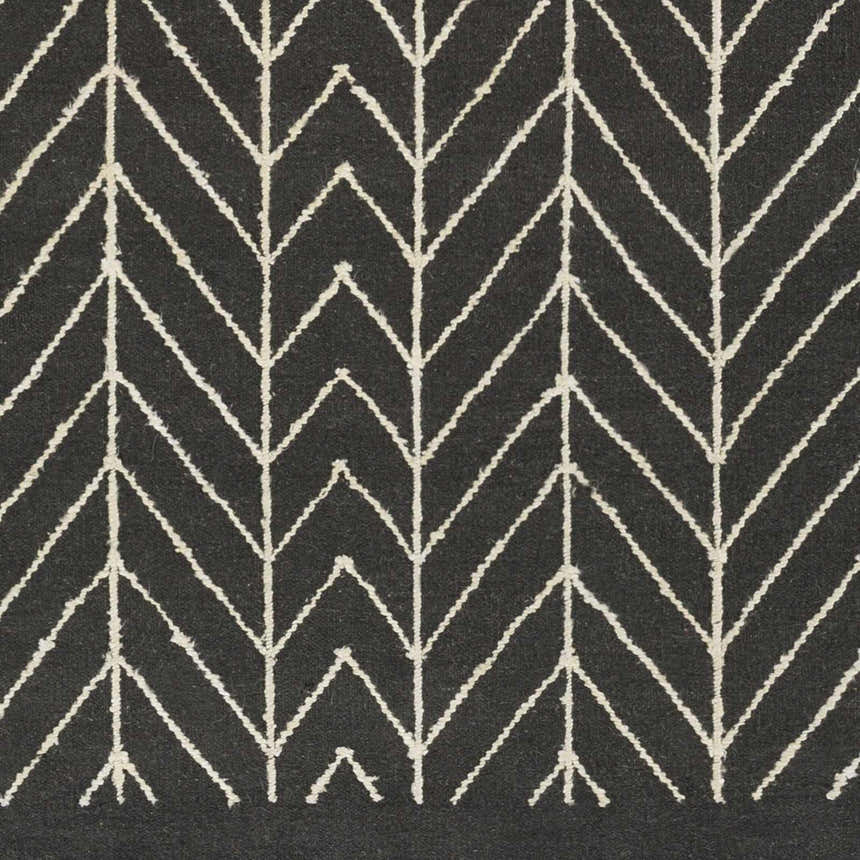Close-up of the Clymer Wool Rug. Black rug with off-white geometric, arrow-like, bohemian pattern. Hand woven texture. Swatch