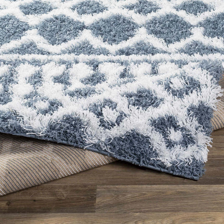 Close-up of the Camp Shag Area Rug, denim and white shag rug with a geometric diamond pattern. Fold