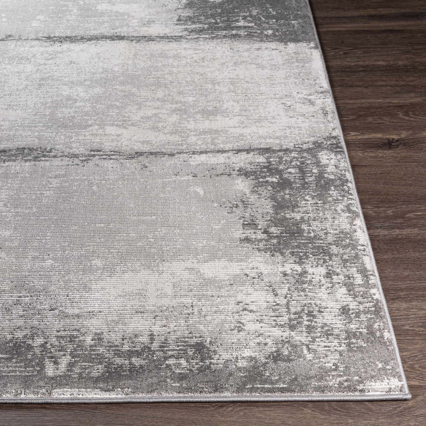 Close-up of the Coombs Area Rug, showcasing its charcoal, gray, and light gray abstract pattern and machine-woven texture. Front