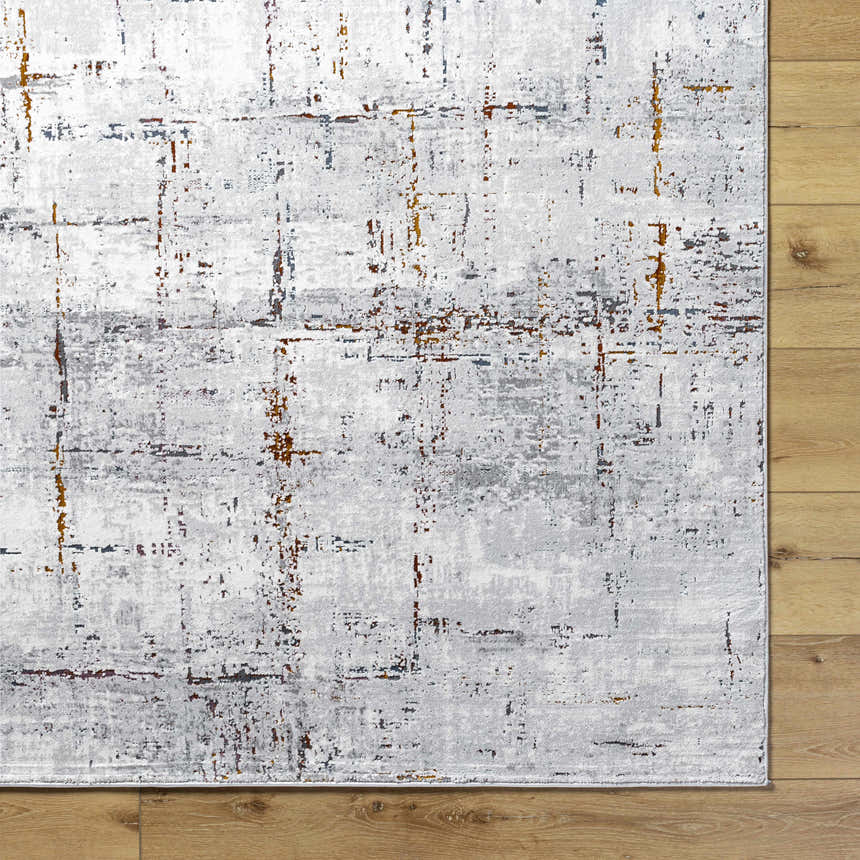 Close-up of Concordia Faux Silk Rug showing gray, burnt orange, and charcoal abstract pattern on wood floor. Corner