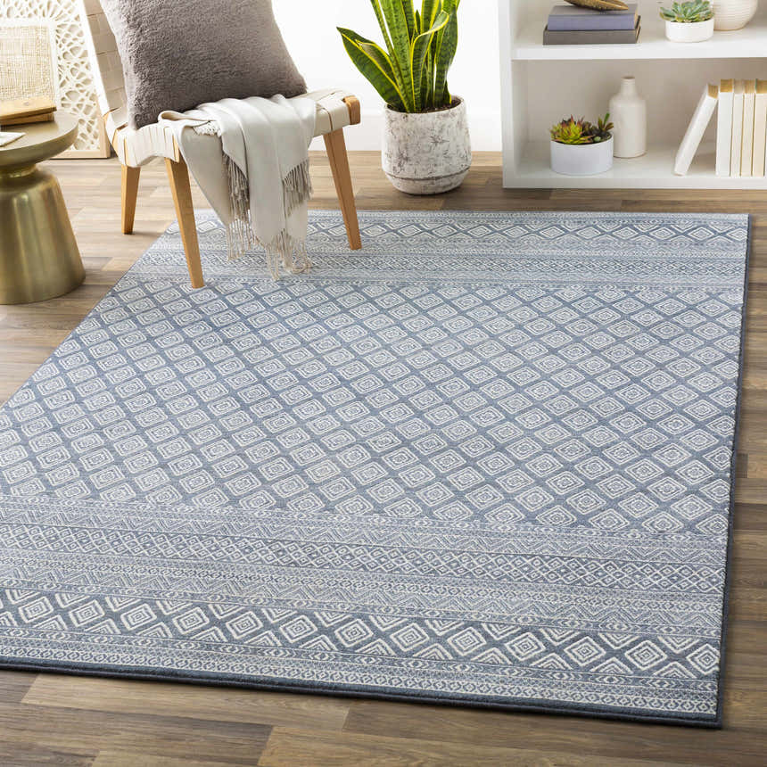 Farmhouse living room with blue and ivory Centertown Area Rug, chair, side table, and bookshelf. Roomscene-Rectangle