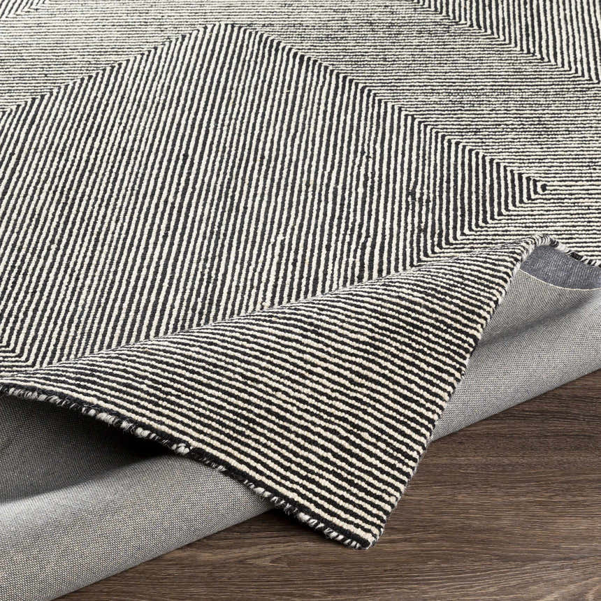 Close-up of the hand-tufted Conshohocken Area Rug; black and cream wool with a geometric, striped Moroccan design. Fold