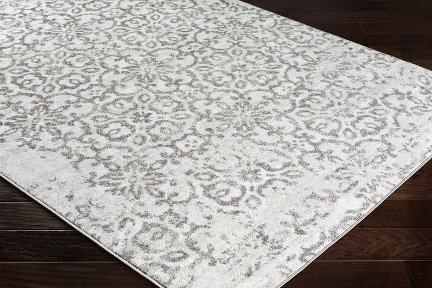 Close-up of the Cordele Area Rug in charcoal and gray, featuring a traditional floral pattern on dark wood floors. Corner