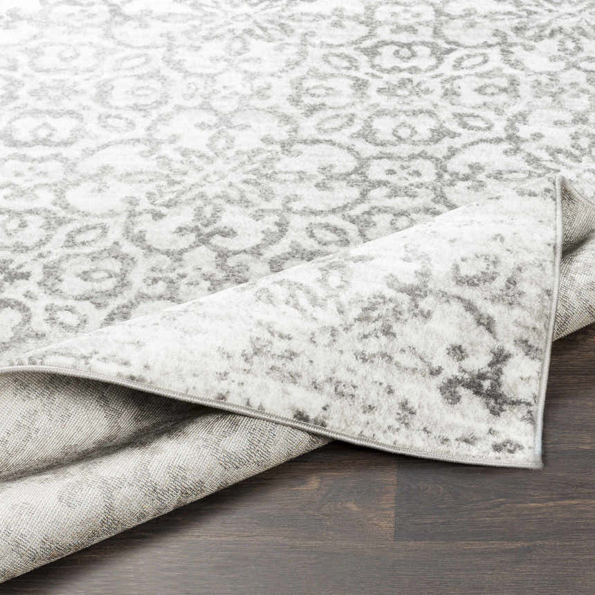 Close-up of the Cordele Area Rug showing its gray and white traditional floral pattern and soft, plush texture. Fold