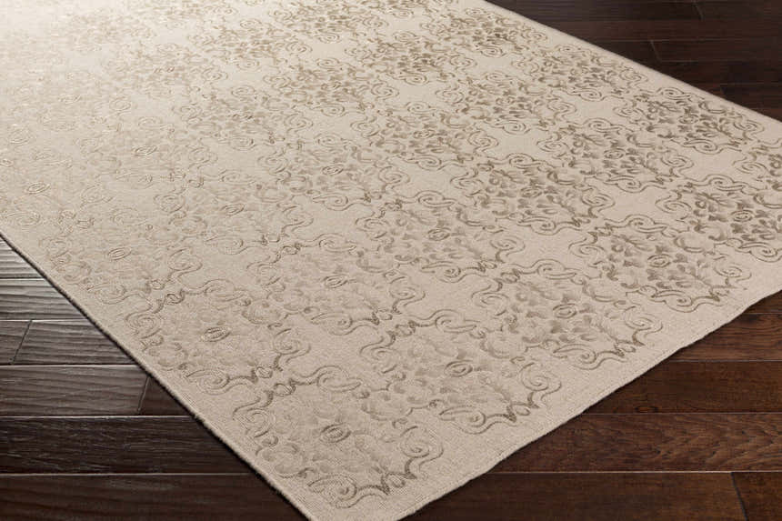 Close-up of the Countyline Area Rug, a hand-woven wool rug with a subtle beige floral pattern on dark wood floors. Corner
