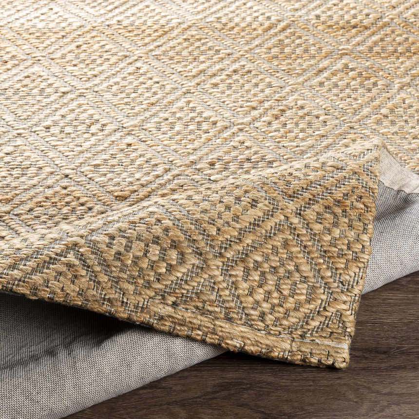 Close-up of the Buwoi Hand Woven Tan Jute Rug showing the diamond pattern and natural fiber texture. Clearance rug. Fold